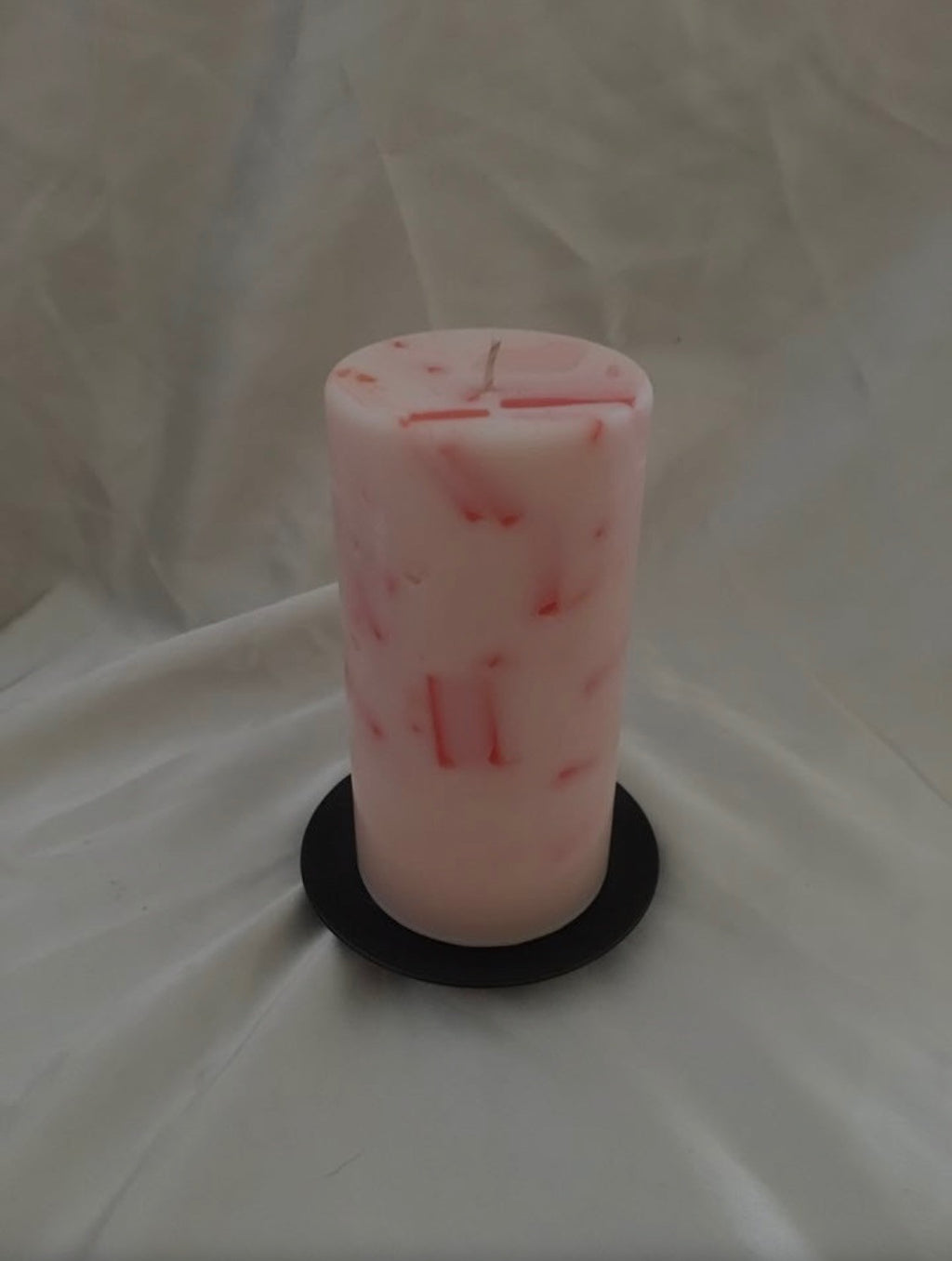 Pink and white marbled pillar candle on a dark round base