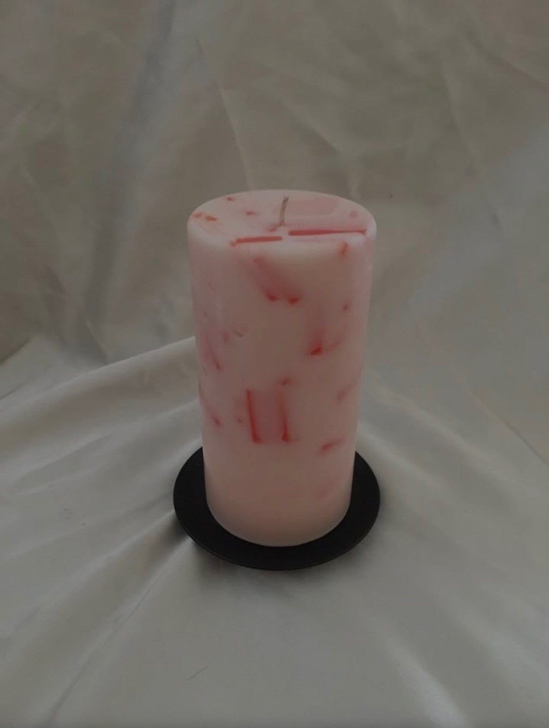 Pink and white marbled pillar candle on a dark round base